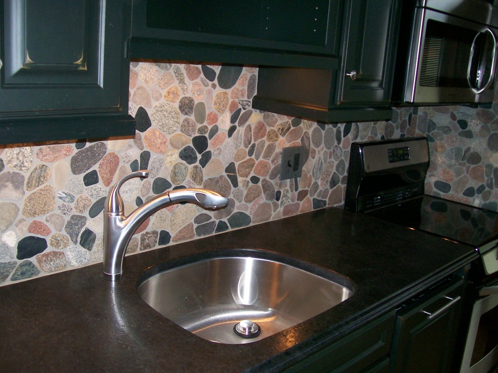 Mid-sized mountain style single-wall medium tone wood floor enclosed kitchen photo with an undermount sink, raised-panel cabinets, black cabinets, granite countertops, gray backsplash, stone tile backsplash, stainless steel appliances and no island
