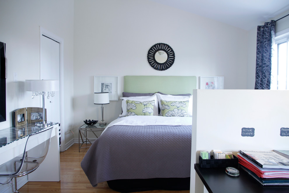 This is an example of a contemporary bedroom in Montreal with white walls and medium hardwood floors.