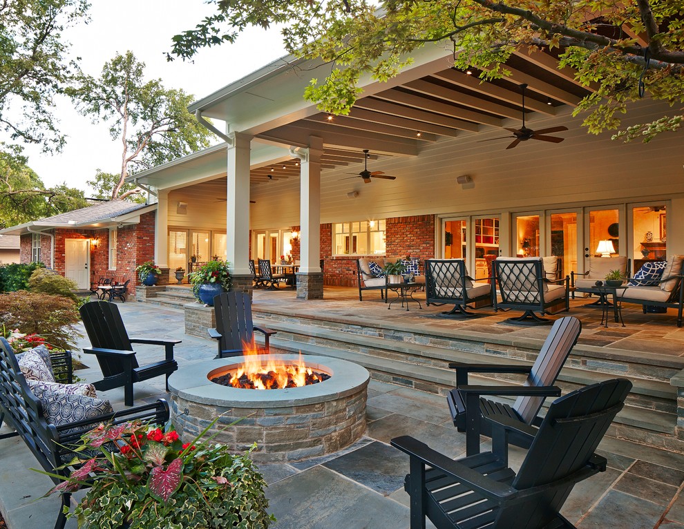 This is an example of an expansive traditional backyard patio in Dallas with natural stone pavers and a roof extension.