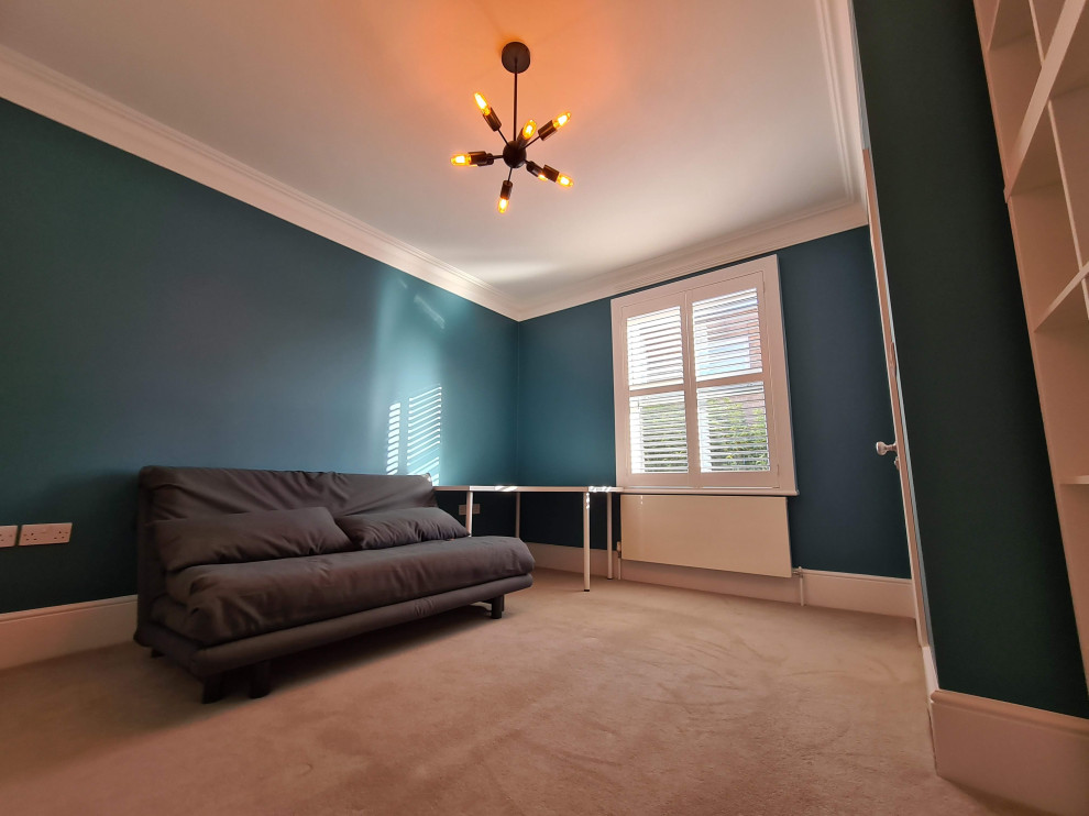 Ejemplo de estudio minimalista de tamaño medio con paredes azules, moqueta, escritorio independiente, suelo beige y bandeja