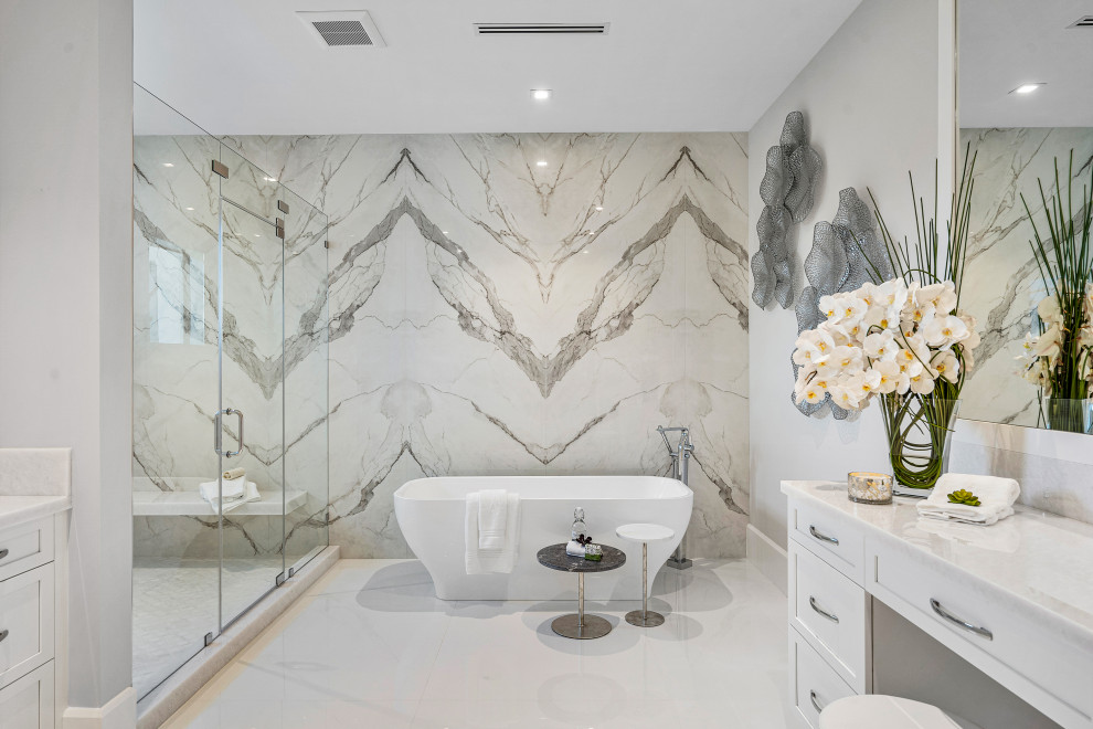Inspiration for an expansive traditional ensuite bathroom in Miami with beaded cabinets, white cabinets, a freestanding bath, an alcove shower, a one-piece toilet, stone slabs, beige walls, marble flooring, a built-in sink, marble worktops, beige floors, a hinged door, white worktops, a single sink and a built in vanity unit.