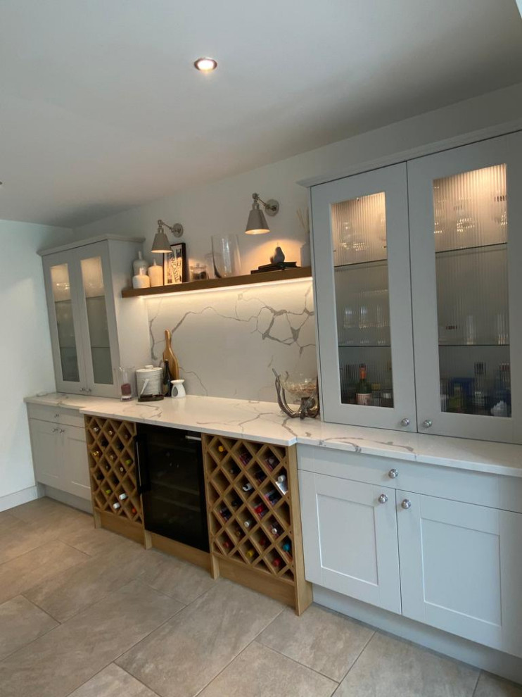 This is an example of a contemporary single-wall wet bar in Other with white cabinets, quartz worktops and shaker cabinets.