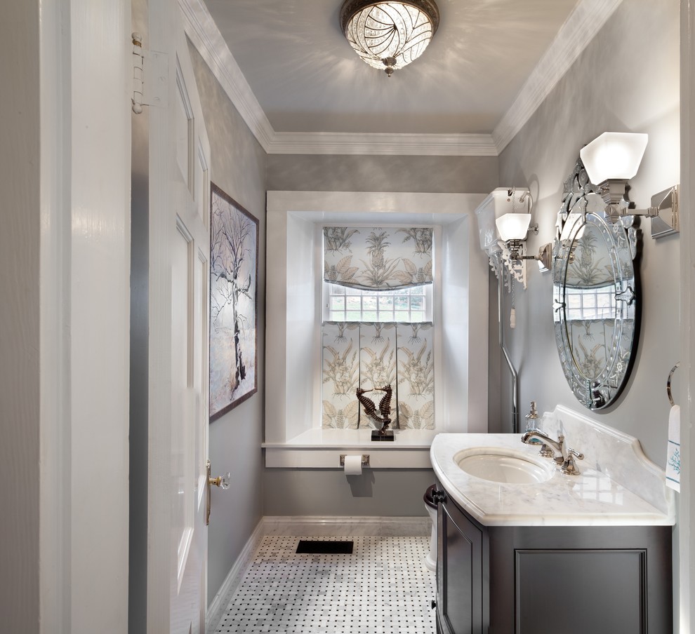 This is an example of a large traditional powder room in DC Metro with furniture-like cabinets, dark wood cabinets, black and white tile, grey walls, marble floors, an undermount sink, marble benchtops, multi-coloured floor and white benchtops.