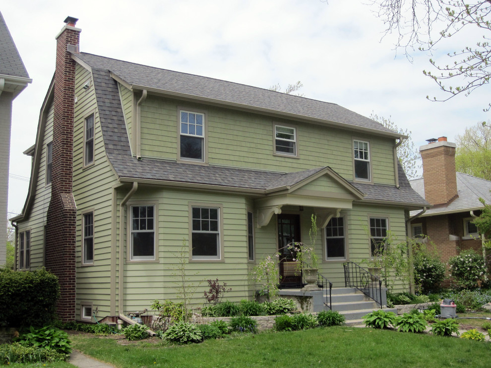 This is an example of a mid-sized traditional two-storey green house exterior in Other with concrete fiberboard siding, a gambrel roof and a shingle roof.