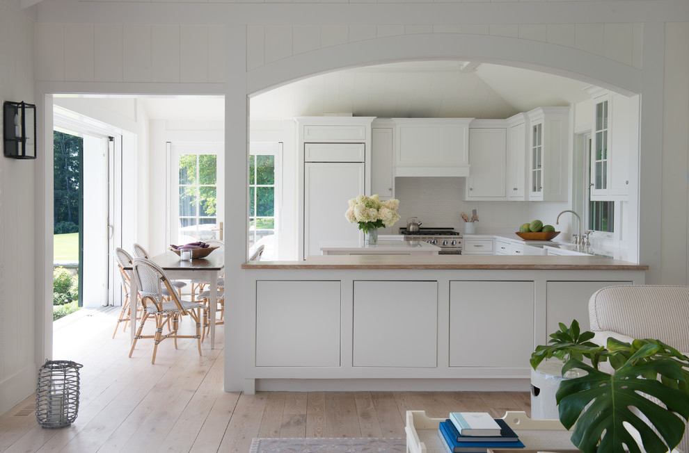 Large country galley eat-in kitchen in San Francisco with a drop-in sink, flat-panel cabinets, white cabinets, wood benchtops, white splashback, stainless steel appliances, plywood floors, with island, brown floor and white benchtop.