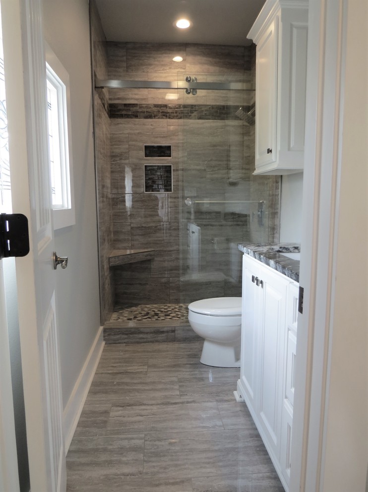 Inspiration for a mid-sized modern master bathroom in Little Rock with raised-panel cabinets, white cabinets, an alcove shower, a one-piece toilet, gray tile, porcelain tile, grey walls, porcelain floors, an undermount sink, granite benchtops, grey floor, a sliding shower screen and multi-coloured benchtops.