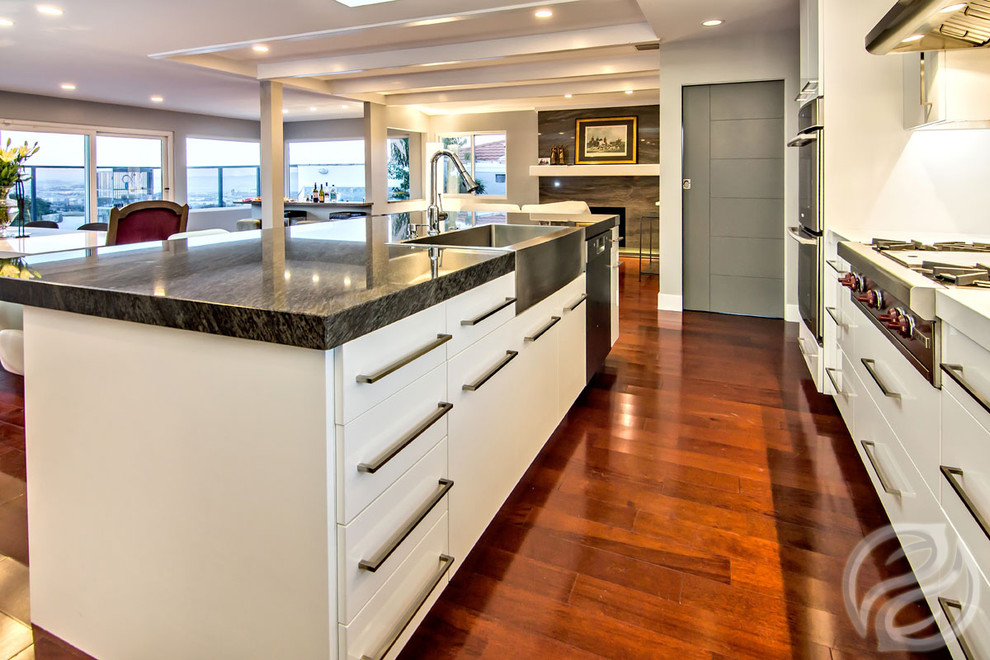 Mid-sized contemporary l-shaped open plan kitchen in Chicago with an undermount sink, flat-panel cabinets, white cabinets, marble benchtops, beige splashback, glass tile splashback, stainless steel appliances, dark hardwood floors and with island.