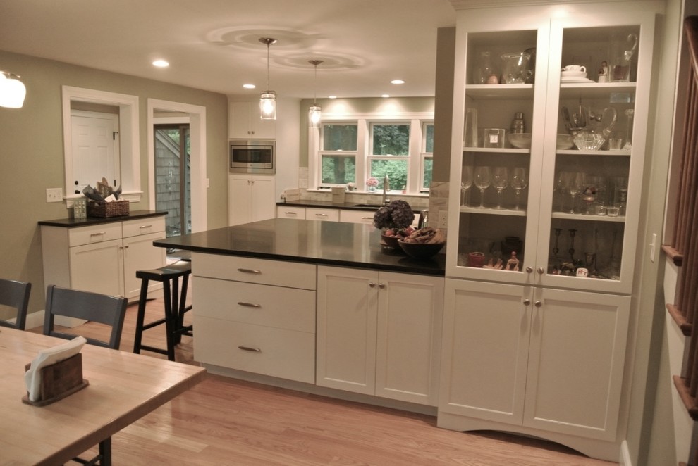 Eat-in kitchen - transitional u-shaped light wood floor eat-in kitchen idea in Boston with an undermount sink, shaker cabinets, white cabinets, beige backsplash, porcelain backsplash, stainless steel appliances, a peninsula and black countertops