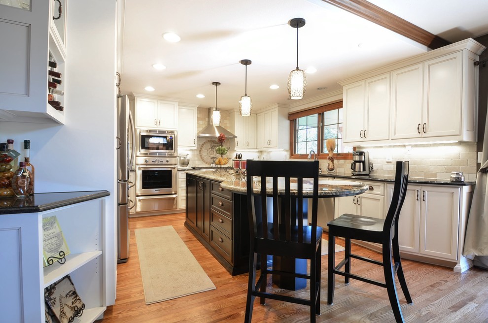 Large transitional galley medium tone wood floor eat-in kitchen photo in Denver with an undermount sink, white cabinets, granite countertops, beige backsplash, stone tile backsplash, stainless steel appliances and an island