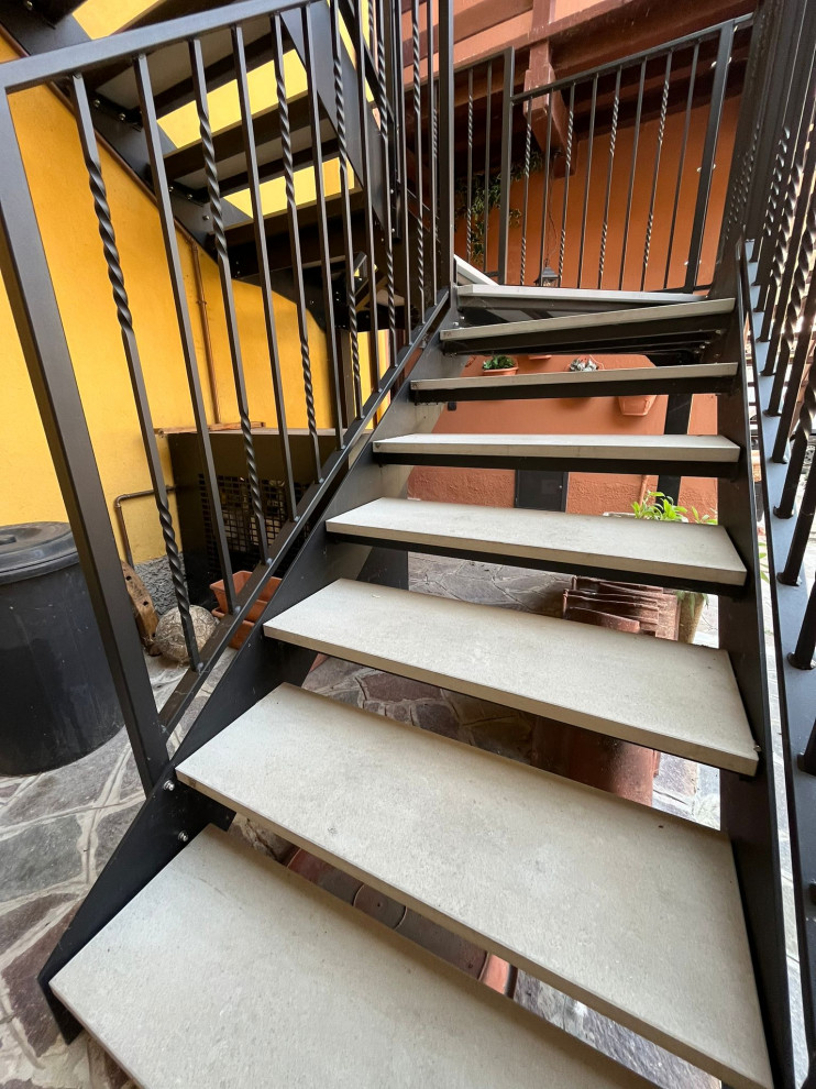 На фото: большая п-образная лестница в стиле лофт с ступенями из травертина и металлическими перилами с