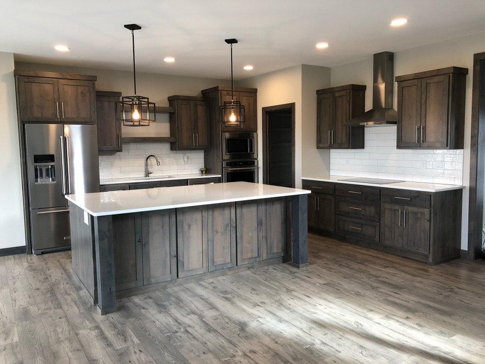 Eat-in kitchen - medium tone wood floor eat-in kitchen idea with an undermount sink, shaker cabinets, medium tone wood cabinets, white backsplash, subway tile backsplash, stainless steel appliances, an island and white countertops