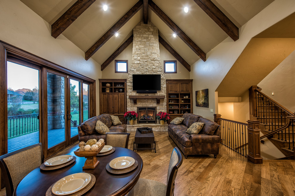 Design ideas for a mid-sized traditional open concept family room in Other with a standard fireplace, a stone fireplace surround, a wall-mounted tv, beige walls and medium hardwood floors.