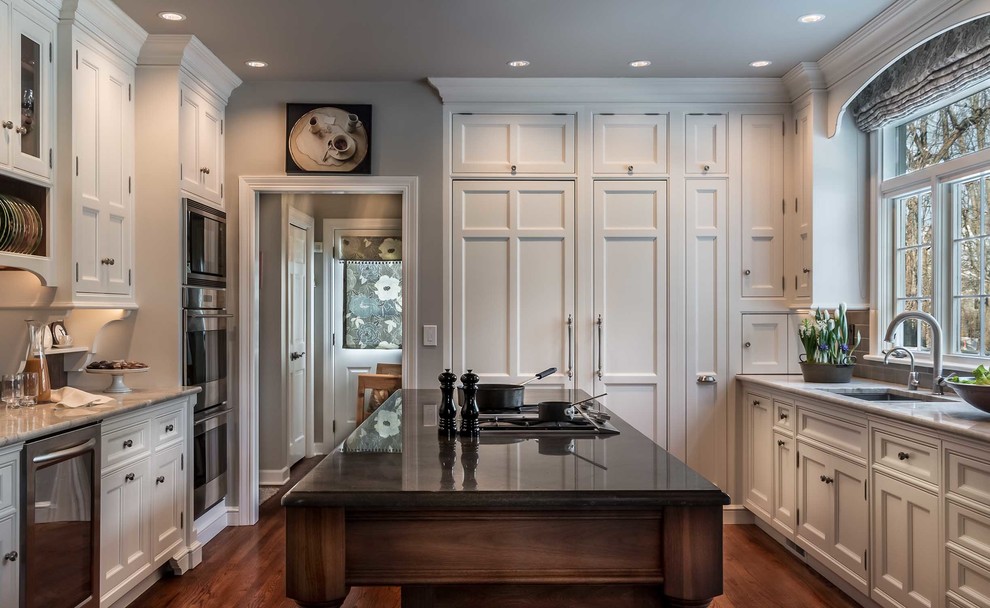 Mid-sized traditional l-shaped eat-in kitchen in Chicago with an undermount sink, beaded inset cabinets, white cabinets, quartz benchtops, brown splashback, stone tile splashback, panelled appliances, medium hardwood floors and with island.