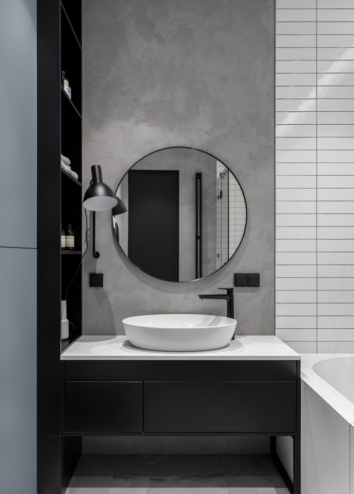 This is an example of a small contemporary master bathroom in Moscow with flat-panel cabinets, black cabinets, an alcove tub, an alcove shower, a wall-mount toilet, white tile, grey walls, porcelain floors, a drop-in sink, solid surface benchtops, grey floor, a hinged shower door, white benchtops, a single vanity and a freestanding vanity.