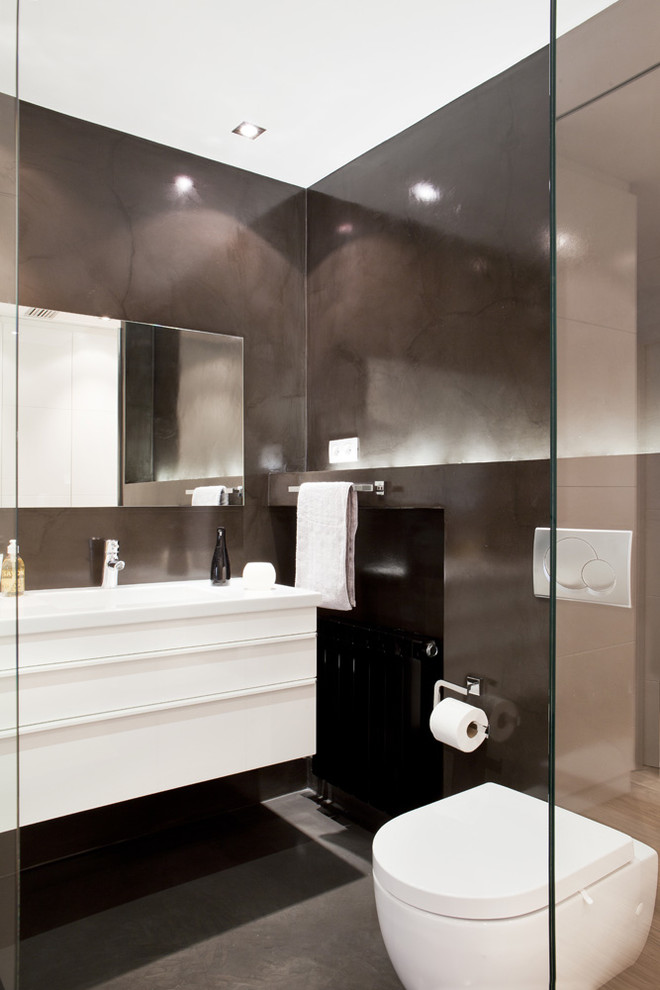 Design ideas for a mid-sized contemporary powder room in Barcelona with flat-panel cabinets, white cabinets, a wall-mount toilet, black walls and an integrated sink.