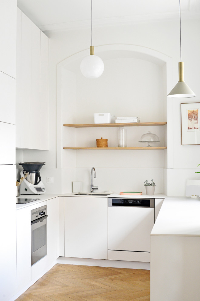 Design ideas for a mid-sized contemporary u-shaped open plan kitchen in Strasbourg with an integrated sink, white cabinets, solid surface benchtops, white splashback, panelled appliances, light hardwood floors and white benchtop.