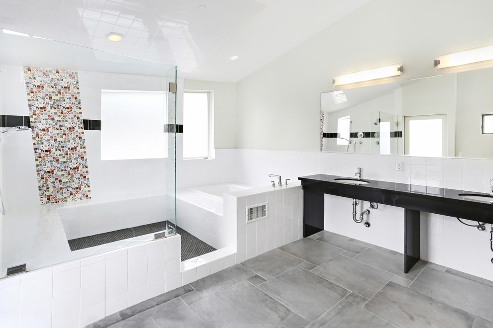 This is an example of a mid-sized modern master bathroom in Los Angeles with a drop-in tub, an open shower, a two-piece toilet, black and white tile, porcelain tile, grey walls, porcelain floors, an undermount sink, solid surface benchtops, grey floor and an open shower.