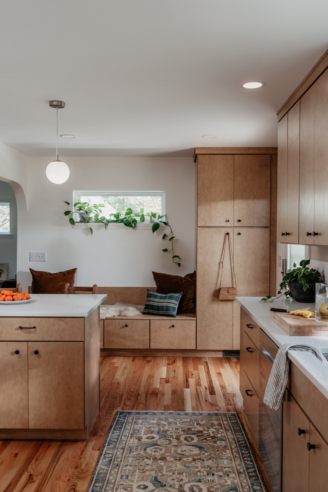 Example of a mid-sized 1950s l-shaped medium tone wood floor kitchen pantry design in Detroit with an undermount sink, flat-panel cabinets, light wood cabinets, quartz countertops, white backsplash, quartz backsplash, stainless steel appliances, a peninsula and white countertops