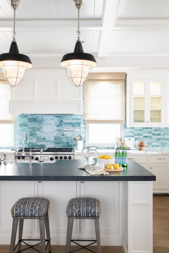 Large beach style u-shaped eat-in kitchen in Los Angeles with a farmhouse sink, recessed-panel cabinets, white cabinets, soapstone benchtops, blue splashback, ceramic splashback, stainless steel appliances, light hardwood floors, with island, beige floor and black benchtop.