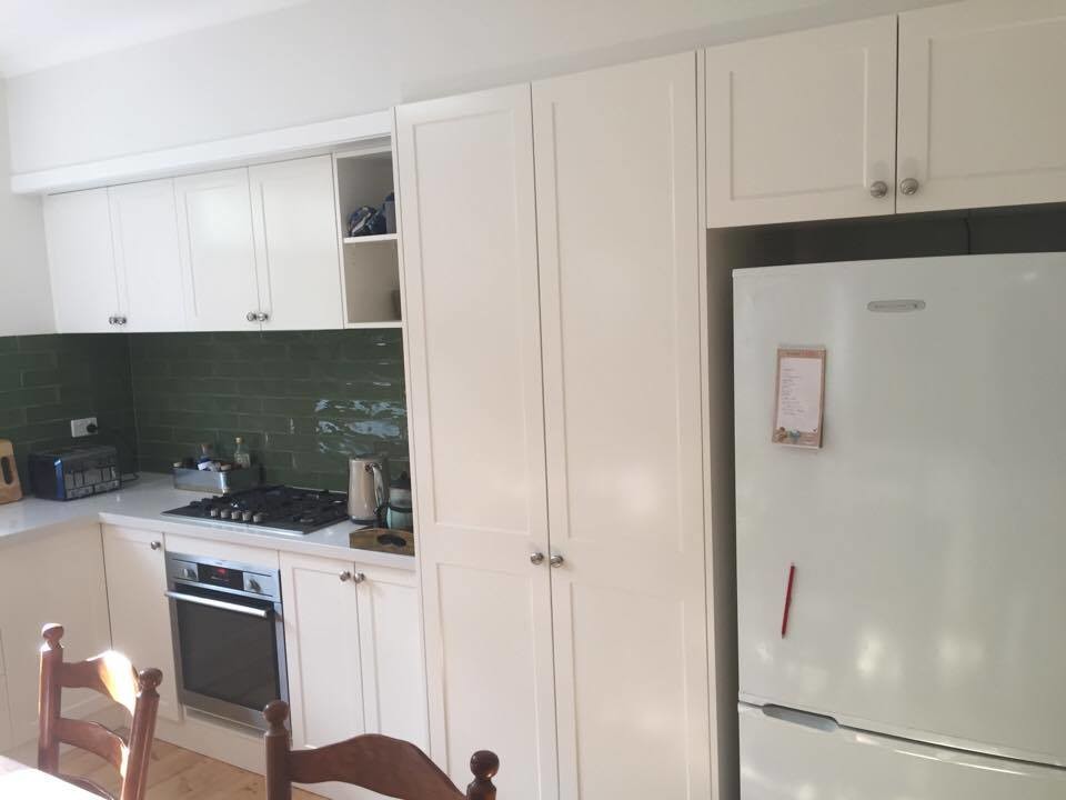 Mid-sized country u-shaped eat-in kitchen in Melbourne with a single-bowl sink, shaker cabinets, white cabinets, granite benchtops, green splashback, ceramic splashback, stainless steel appliances, light hardwood floors and white benchtop.