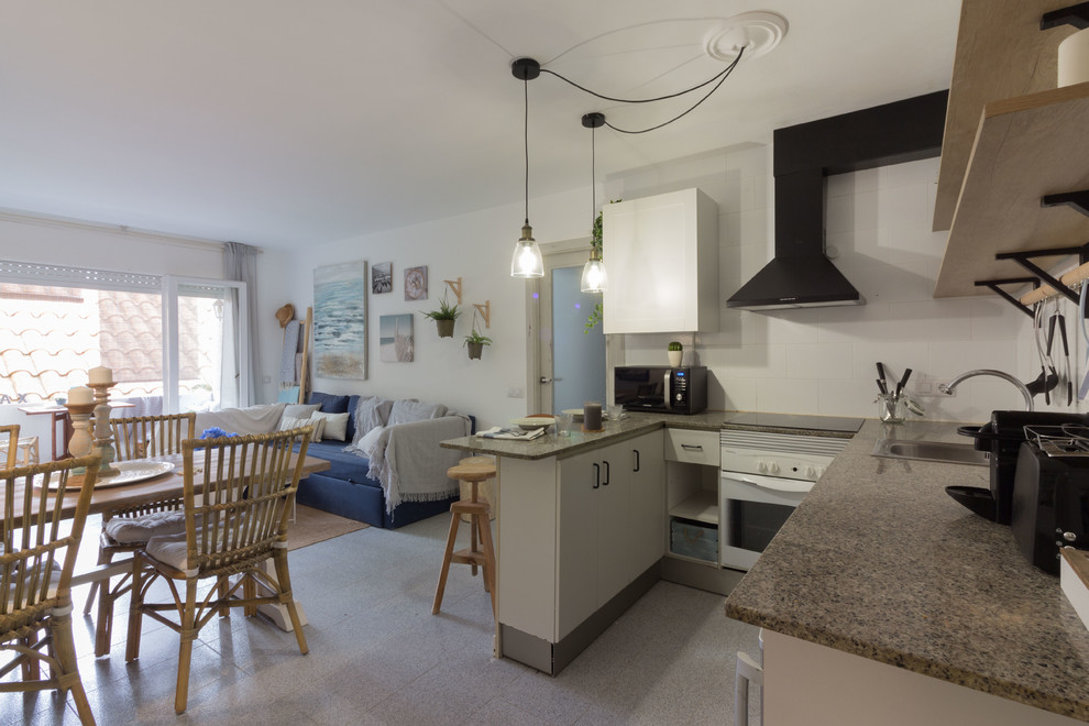 Small beach style u-shaped open plan kitchen in Other with a drop-in sink, open cabinets, white cabinets, granite benchtops, white splashback, ceramic splashback, stainless steel appliances, porcelain floors, a peninsula, grey floor and grey benchtop.