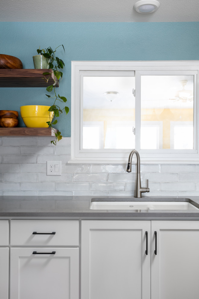 Eat-in kitchen - mid-sized transitional l-shaped light wood floor and brown floor eat-in kitchen idea in Denver with an undermount sink, shaker cabinets, white cabinets, quartz countertops, white backsplash, porcelain backsplash, stainless steel appliances, an island and gray countertops