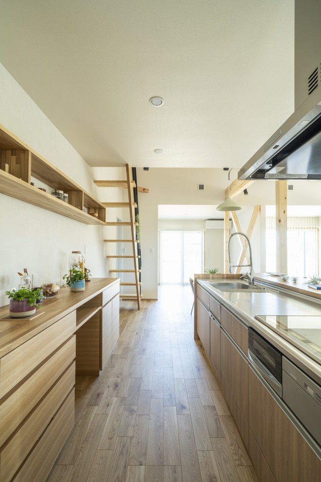Mid-sized asian single-wall open plan kitchen in Other with an integrated sink, beaded inset cabinets, medium wood cabinets, solid surface benchtops, white splashback, stainless steel appliances, light hardwood floors, a peninsula, brown floor and brown benchtop.