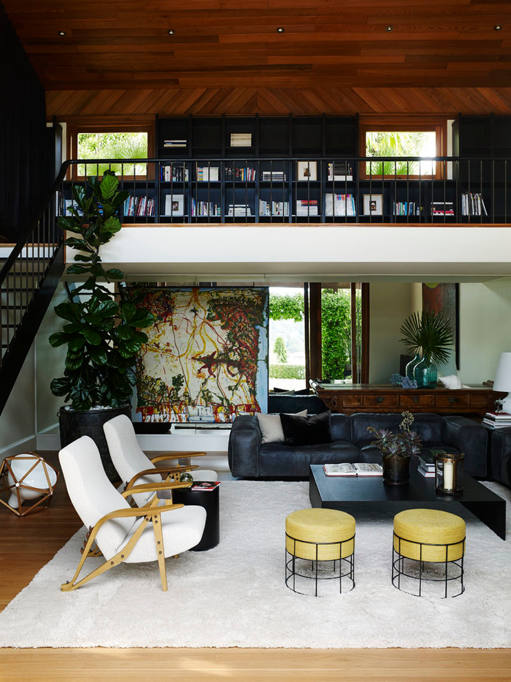 This is an example of a contemporary open concept living room in Sydney with a library, white walls, medium hardwood floors and no tv.