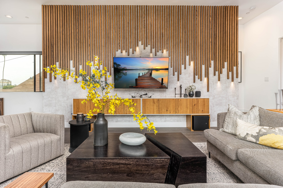 Aménagement d'un grand salon contemporain ouvert avec un mur gris, sol en stratifié et un téléviseur fixé au mur.