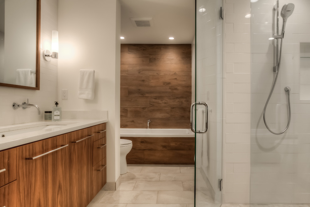 Design ideas for an expansive contemporary master bathroom in Portland with flat-panel cabinets, medium wood cabinets, an alcove tub, a curbless shower, a one-piece toilet, white tile, ceramic tile, white walls, porcelain floors, an undermount sink and engineered quartz benchtops.