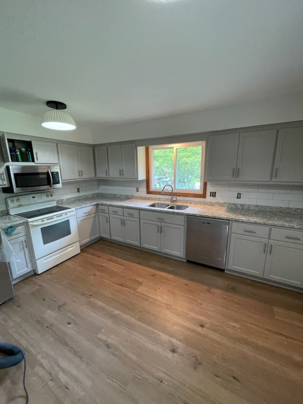 Kitchen - mid-sized l-shaped laminate floor kitchen idea with shaker cabinets, white cabinets, laminate countertops, cement tile backsplash and no island