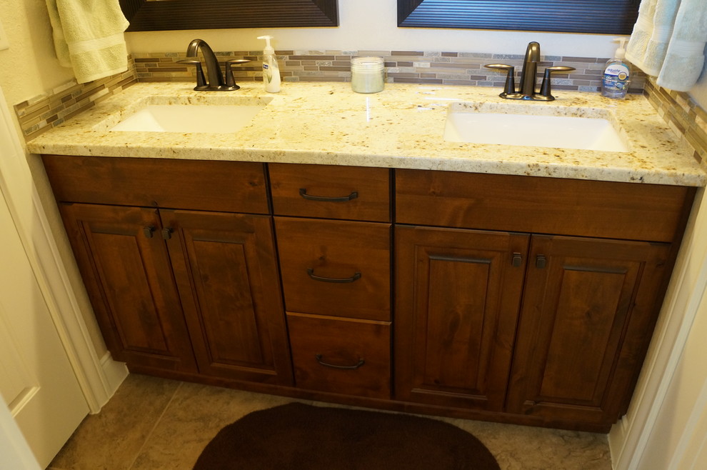 Transitional porcelain tile bathroom photo in Austin with raised-panel cabinets, dark wood cabinets, an undermount sink and granite countertops