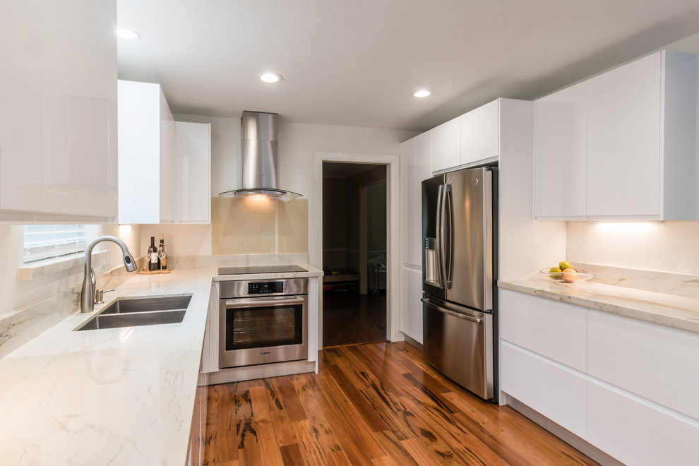 Mid-sized contemporary u-shaped eat-in kitchen in Houston with an undermount sink, flat-panel cabinets, white cabinets, quartzite benchtops, beige splashback, glass tile splashback, stainless steel appliances, light hardwood floors and no island.