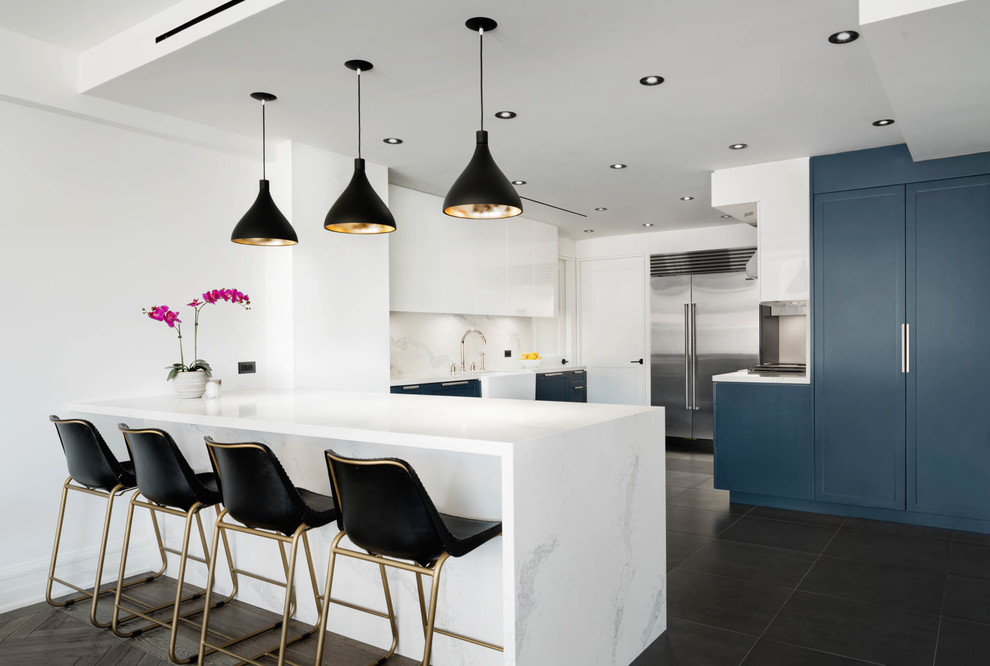 This is an example of a contemporary u-shaped separate kitchen in New York with a farmhouse sink, shaker cabinets, blue cabinets, grey splashback, stainless steel appliances, a peninsula and grey floor.