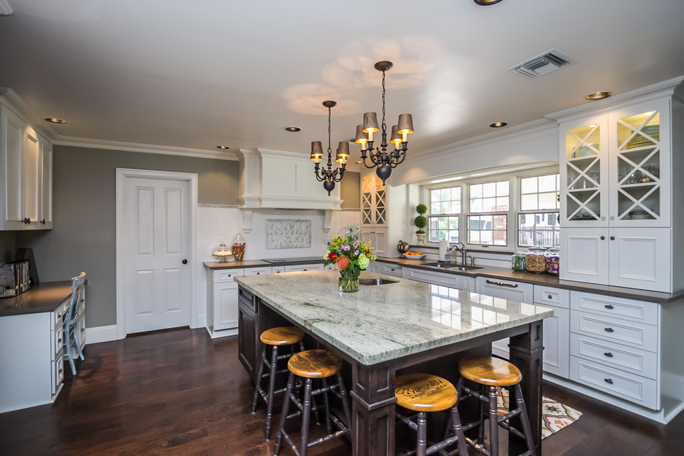 Example of a large transitional u-shaped dark wood floor and brown floor eat-in kitchen design in Phoenix with a double-bowl sink, recessed-panel cabinets, white cabinets, quartzite countertops, white backsplash, ceramic backsplash, paneled appliances and an island