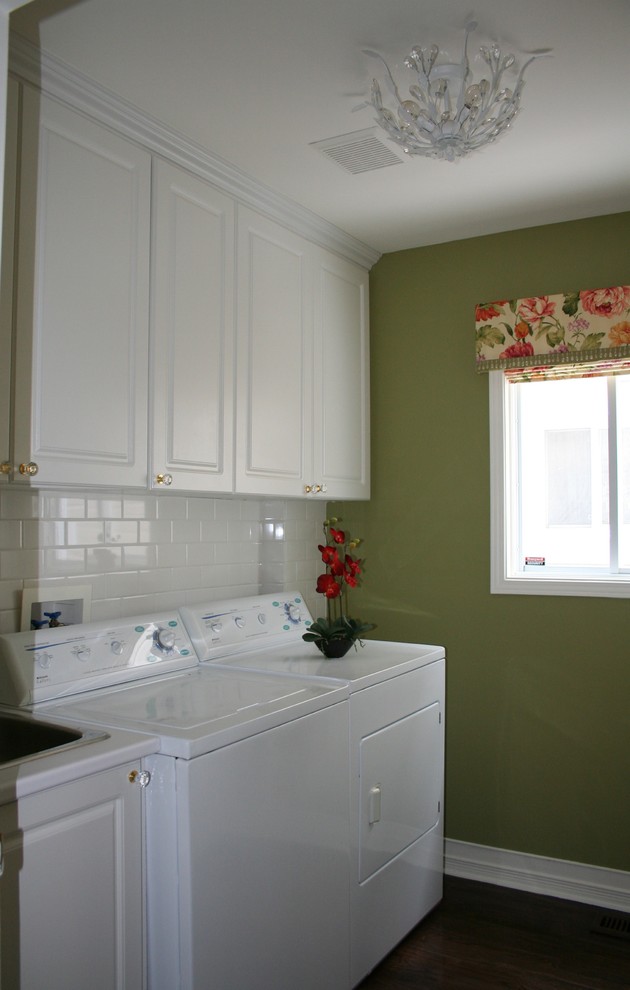 Small traditional single-wall dedicated laundry room in Ottawa with a single-bowl sink, raised-panel cabinets, white cabinets, laminate benchtops, white splashback, subway tile splashback, green walls, dark hardwood floors, a side-by-side washer and dryer, brown floor and white benchtop.