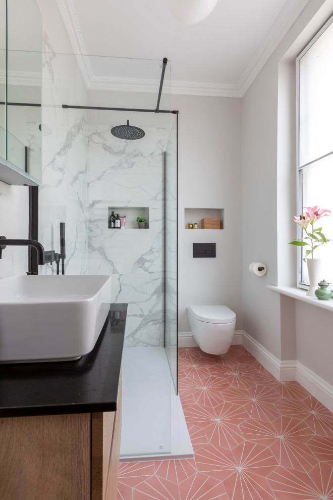 Photo of an eclectic bathroom in London with flat-panel cabinets, medium wood cabinets, a corner shower, white tile, grey walls, a vessel sink, pink floor, an open shower, black benchtops, a single vanity, a floating vanity and a niche.