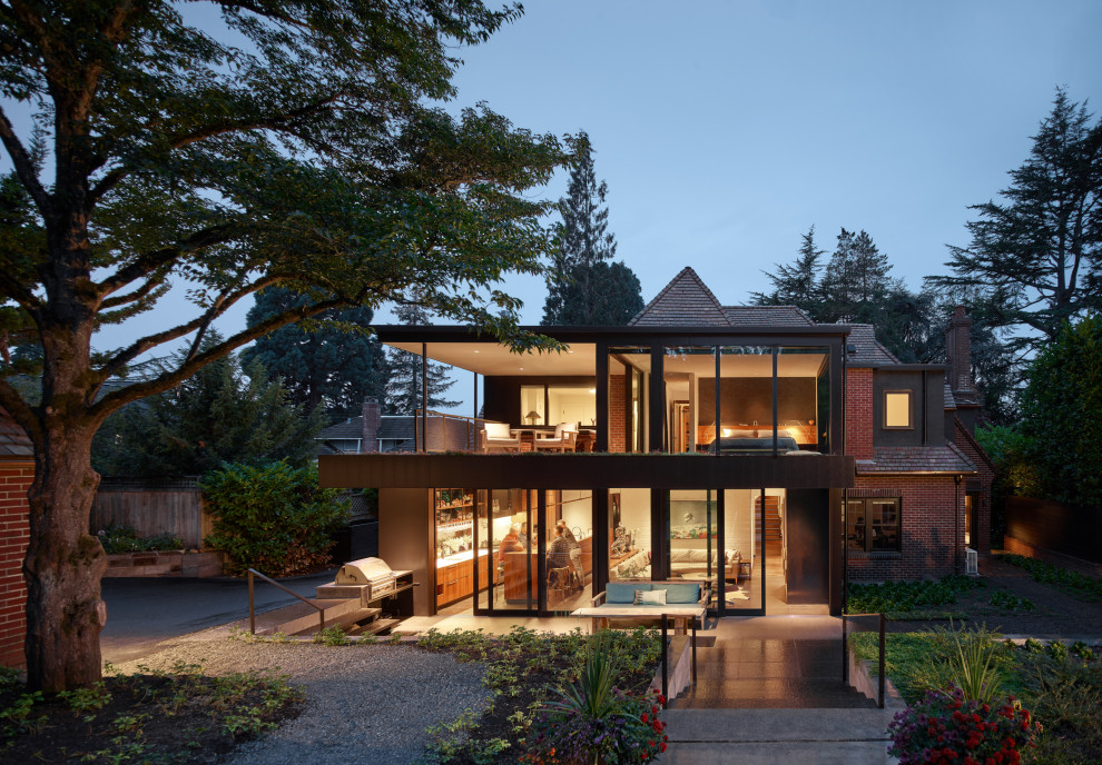 This is an example of a large eclectic two-storey black house exterior in Seattle with metal siding, a flat roof and a tile roof.
