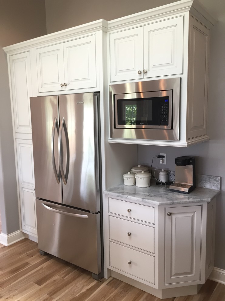 Inspiration for a large transitional u-shaped light wood floor open concept kitchen remodel with an undermount sink, beaded inset cabinets, white cabinets, white appliances and a peninsula
