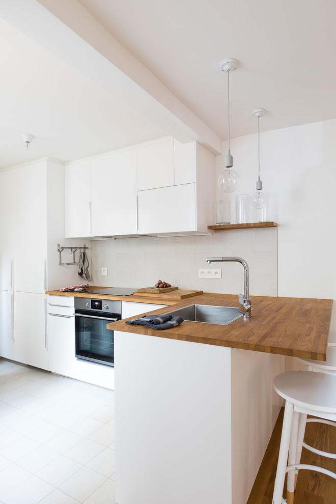 Inspiration for a small contemporary l-shaped open plan kitchen in Paris with an undermount sink, beaded inset cabinets, white cabinets, wood benchtops, stainless steel appliances, white floor and ceramic floors.