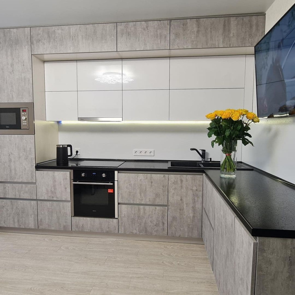 Design ideas for a large scandinavian l-shaped eat-in kitchen in Novosibirsk with a drop-in sink, flat-panel cabinets, grey cabinets, solid surface benchtops, white splashback, limestone splashback, black appliances, laminate floors, no island, yellow floor and black benchtop.