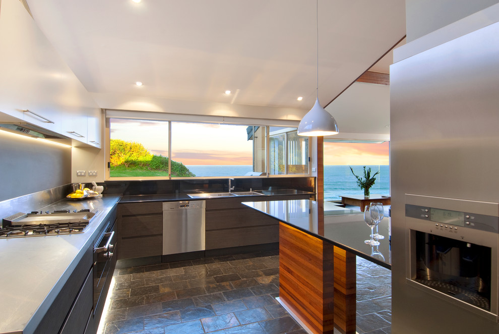 Inspiration for a large contemporary l-shaped open plan kitchen in Sydney with a double-bowl sink, flat-panel cabinets, grey cabinets, grey splashback, stone slab splashback, stainless steel appliances, slate floors, with island and stainless steel benchtops.