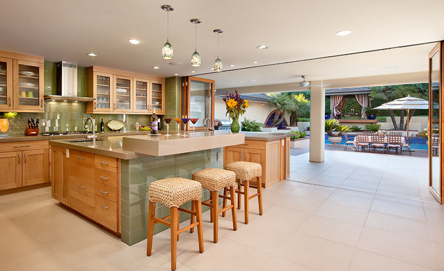 Design ideas for a large tropical u-shaped eat-in kitchen in Santa Barbara with an undermount sink, shaker cabinets, light wood cabinets, quartz benchtops, green splashback, glass tile splashback, stainless steel appliances, porcelain floors, with island and beige floor.