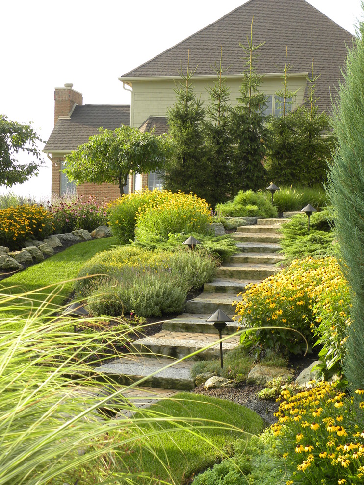 Photo of a traditional sloped garden in Cincinnati with natural stone pavers.