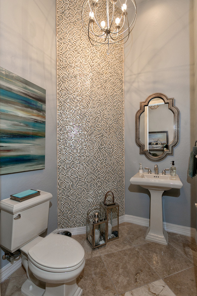 Photo of a small transitional powder room in Phoenix with a two-piece toilet, multi-coloured tile, glass tile, grey walls, travertine floors, a pedestal sink and beige floor.