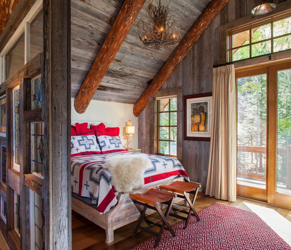 This is an example of a country bedroom in Denver with white walls and medium hardwood floors.