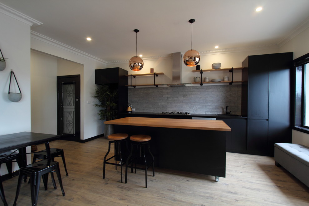 Inspiration for a mid-sized industrial single-wall open plan kitchen in Melbourne with a single-bowl sink, open cabinets, black cabinets, laminate benchtops, grey splashback, subway tile splashback, stainless steel appliances, laminate floors and with island.