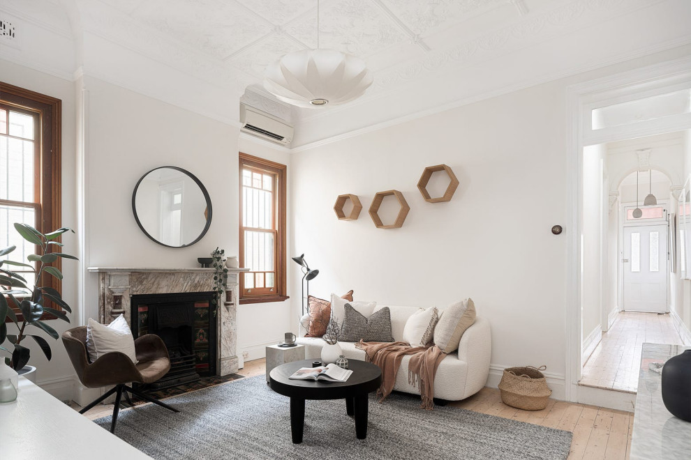 Immagine di un piccolo soggiorno tradizionale chiuso con pareti bianche, parquet chiaro, camino classico, cornice del camino in pietra e pavimento marrone