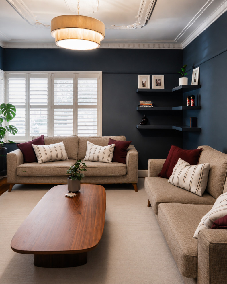 Mid-sized transitional enclosed living room in Melbourne with blue walls, medium hardwood floors, a standard fireplace, a plaster fireplace surround, a wall-mounted tv and beige floor.