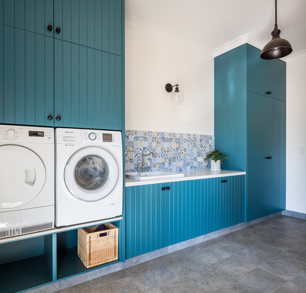 This is an example of a country laundry room in Perth with a drop-in sink, louvered cabinets, green cabinets, quartz benchtops, multi-coloured walls, a side-by-side washer and dryer and grey benchtop.